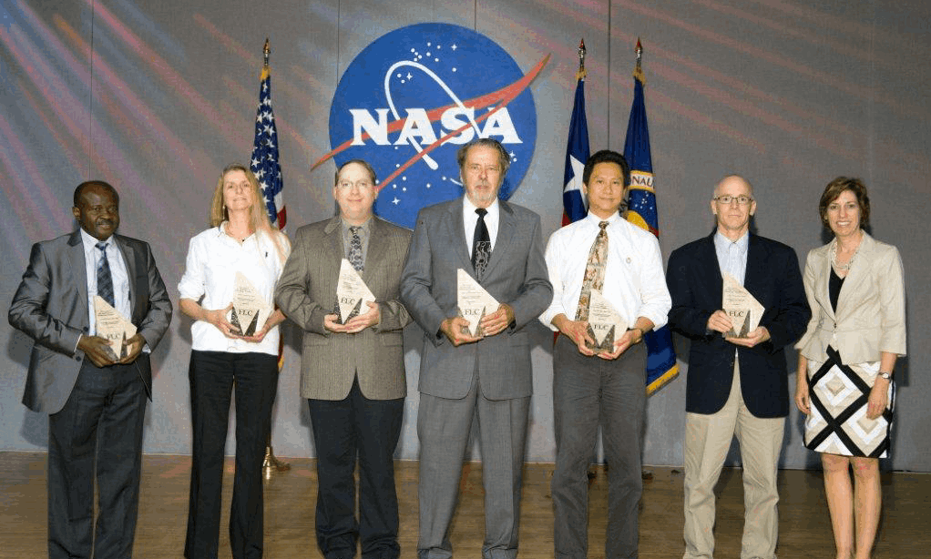 Complete archival awards group photograph in front of the NASA emblem
